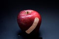 Red apple with bandage on dark background Royalty Free Stock Photo