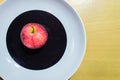 Red apple on the black and white plate with wood background. Royalty Free Stock Photo