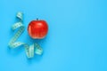 Red apple and blue measuring tape on a pastel blue background. The concept of diet and weight loss. Creative layout. Top view, Royalty Free Stock Photo