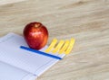 Red apple, blue pen And a white note book with a wooden background,selective Focus Royalty Free Stock Photo