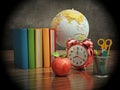 Red apple, books, pencil holder, model globe and alarm clock on green board. 3D illustration