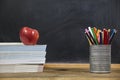 Red apple, books and penciles on wooden table and blackdoard background.school for kids Royalty Free Stock Photo