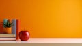 Red apple, books, and potted plant on a white surface against an orange backdrop. Royalty Free Stock Photo
