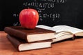 Red apple on books and school blackboard with mathematical equations in the classroom Royalty Free Stock Photo
