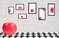Red apple on chessboard pattern of table floor with black picture frames on white brick wall decoration
