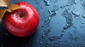 A red apple covered in raindrops on a wet surface, top view