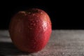 Red apple covered in water drops on black background with wooden floor. Health Concept with refreshing fruit