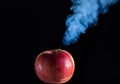 Red apple with cuts on a black background is smoking