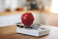 Red apple on a digital scale with warm kitchen lighting highlighting freshness Royalty Free Stock Photo