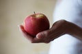 Red apple in female palm on the background of a girl in a white shirt. Side view Royalty Free Stock Photo