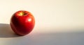 Red apple on a flat, light background, casting a soft shadow. It has a smooth surface Royalty Free Stock Photo
