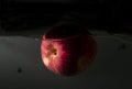 Red apple floating inside the water with dark background