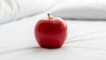 Red apple with a glossy surface positioned on a white smooth bed sheet Royalty Free Stock Photo