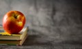 Red apple on gray background and books