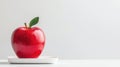 A red apple with a green leaf sits on a white plate. Royalty Free Stock Photo