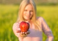 A healthy attractive woman eatiing a red apple. Green summer field.