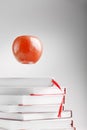 A red Apple hangs above the books on a white background