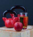 Red apple, juice, and kettlebells on chopping board Royalty Free Stock Photo