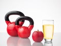 Red apple, juice, and kettlebells on reflective surface Royalty Free Stock Photo