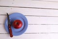 Red apple and a knife on a blue plate on a white timber table Royalty Free Stock Photo