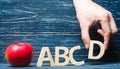 Red apple and letters ABCD. The hand puts the letter D in the al