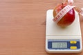 Red apple with measure tape on electronic scale, d