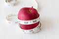 Red apple and measurement tape isolated on melamine wooden plank. Suitable for weight loss diet programme or advertisement.