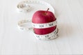 Red apple and measurement tape isolated on white wooden plank. Suitable for weight loss and diet programme advertisement.