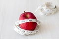 Red apple and measurement tape on melamine wooden plank. Suitable for weight loss diet programme.