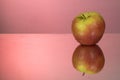 Red apple on mirroring table on mirror red background with reflection isolated close up Royalty Free Stock Photo