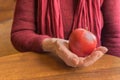 Red apple in old hands of elderly women in red, close up Royalty Free Stock Photo