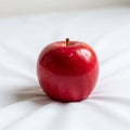 Red apple resting on a soft white fabric casting a subtle shadow Royalty Free Stock Photo