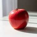 A red apple, smooth-skinned with a short stem, sits on a white Royalty Free Stock Photo