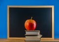 Red apple on a stack of books lying on the background of the chalkboard Royalty Free Stock Photo