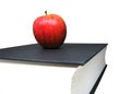 Red apple on top of black hard-cover dictionary book isolated on white background. Royalty Free Stock Photo