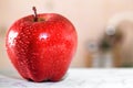 Red Apple with water drops on white table in kitchen Royalty Free Stock Photo