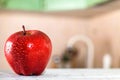 Red Apple with water drops on white table in kitchen Royalty Free Stock Photo