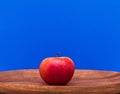 Red apple on a wooden tray on a blue background. Fruits. Harvest, detox.