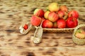 Red apples and autumn flowers lie in a wicker plate on a wooden table. Wicker shoes and apples in a basket. Healthy food Royalty Free Stock Photo