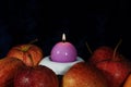 Red apples and a burning candle in a candlestick Royalty Free Stock Photo