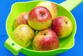 Red apples in green sieve on blue