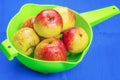 Red apples in green sieve on blue