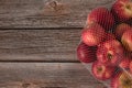 Red apples in mesh bag on wooden table with copy space, top view Royalty Free Stock Photo