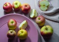 Red apples on pastel pink plate on purple background Royalty Free Stock Photo