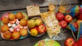 Red apples, pears, tangerines, salt crackers, plastic bag with chips and a plate with cupcakes and candies