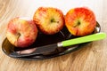 Red apples, table knife in oval dish on wooden table Royalty Free Stock Photo