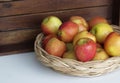 Red appples in basket on white table , wooden background, fruits