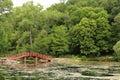 A red arched bridge over a lake leading to forest in Rotary Botanic Gardens in Janesville, wisconsin