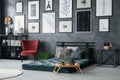 Red armchair next to green mattress in grey bedroom interior with posters on concrete wall. Real photo Royalty Free Stock Photo