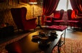 Red armchairs with coffee cups on table in cozy classic interior. Antique living room with red curtains and armchairs.